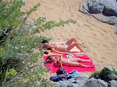 Two nude girls sun bathing on beach.