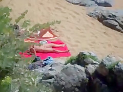 Two nude girls sun bathing on beach.