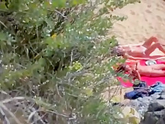 Two nude girls sun bathing on beach.