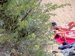 Two nude girls sun bathing on beach.