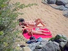 Two nude girls sun bathing on beach.