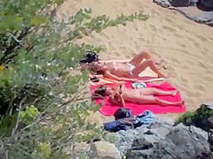 Two nude girls sun bathing on beach.