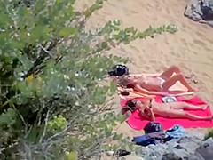 Two nude girls sun bathing on beach.