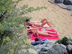 Two nude girls sun bathing on beach.