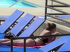 Sexy babe relaxes by the pool