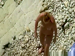 Nudist woman in rocky beach smoking