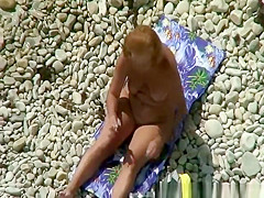 Nudist woman in rocky beach smoking