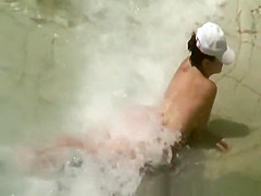 Two nudist women laid down by the water