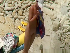 Two nudist women laid down by the water