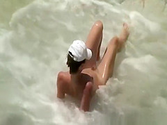 Two nudist women laid down by the water