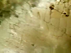 Two nudist women laid down by the water