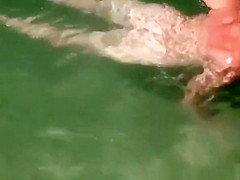 Nudist woman swimming in the beach