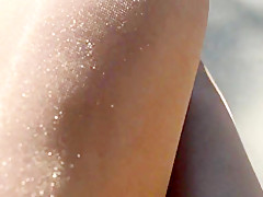 Rubbing shiny pantyhose legs outdoors
