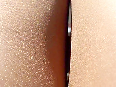Rubbing shiny pantyhose legs outdoors