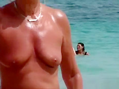 The old woman is walking topless on the beach