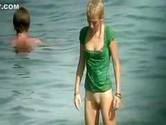 Nudist girl washes a towel in the water