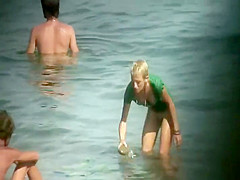 Nudist girl washes a towel in the water