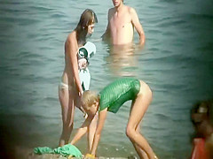 Nudist girl washes a towel in the water