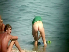 Nudist girl washes a towel in the water