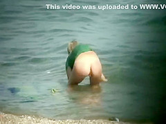 Nudist girl washes a towel in the water