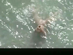 Nude mature woman refreshing in the water