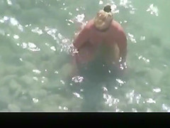 Nude mature woman refreshing in the water