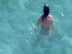 Nudist brunette swims in the water