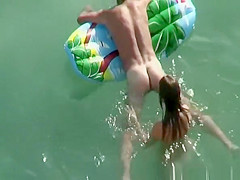 Nudist brunette swims in the water