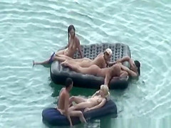 Group of nudist in air mattress in the water