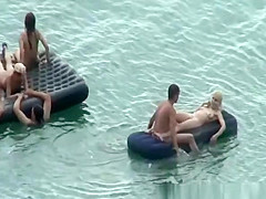 Group of nudist in air mattress in the water