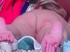 Nudist woman laid down on her belly sunbathing