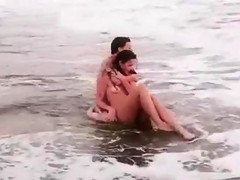 Beautiful naked brunettes splash around in the ocean