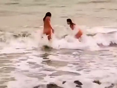 Beautiful naked brunettes splash around in the ocean