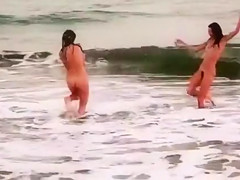 Beautiful naked brunettes splash around in the ocean