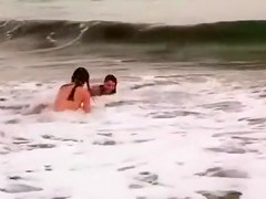 Beautiful naked brunettes splash around in the ocean