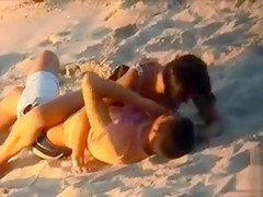 Attractive doll enjoys a man's cock in the sand