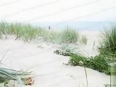 Ebony girl masturbates in the sand while being filmed