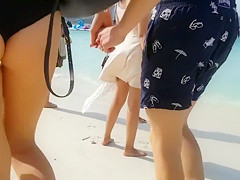 Girlfriend in a tight bikini strolls down the beach with her boy