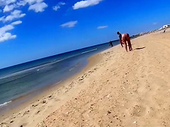 Group of mature nudists walks around the beach naked