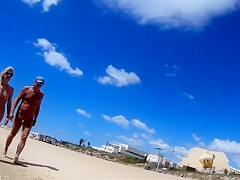 Group of mature nudists walks around the beach naked