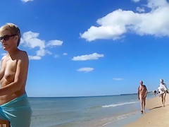 Group of mature nudists walks around the beach naked