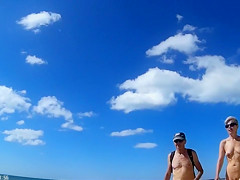 Group of mature nudists walks around the beach naked