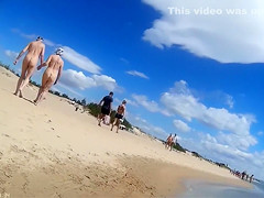 Group of mature nudists walks around the beach naked