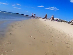 Group of mature nudists walks around the beach naked