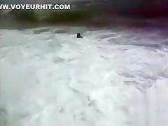 Busty brunette's lower part of a bikini drops as huge waves hit her