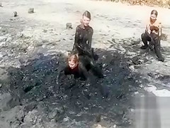 Young ladies coat their bodies in dark mud