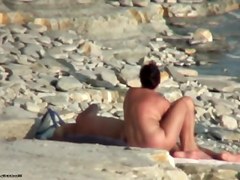 Hot cougar is lying on sand in naked beach video