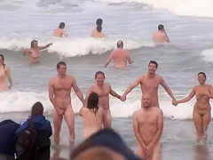 Hundreds of nudist people running into the sea naked
