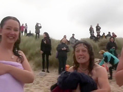 Hundreds of nudist people running into the sea naked