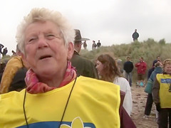 Hundreds of nudist people running into the sea naked